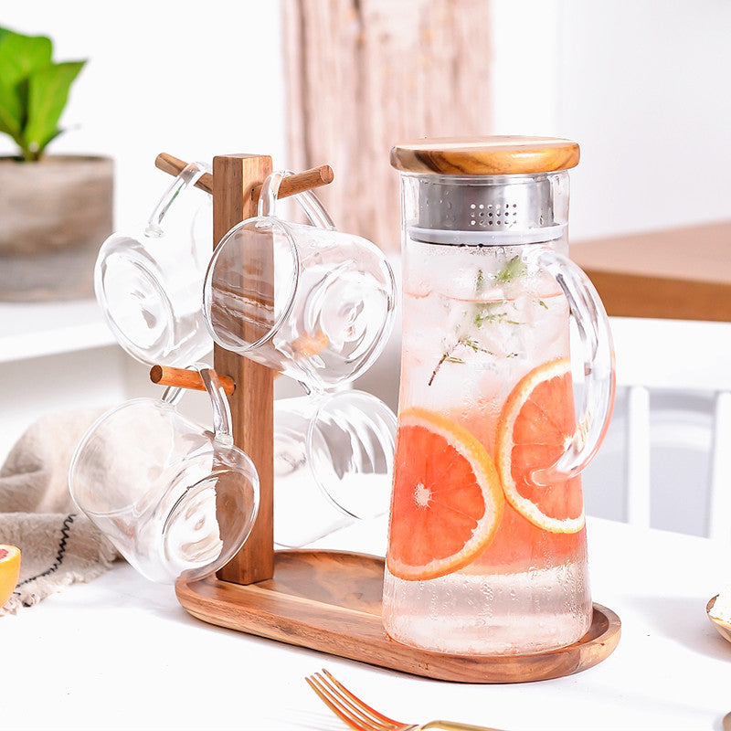 Glass cold water bottle with brown wood stand and metal lid, citrus slices inside