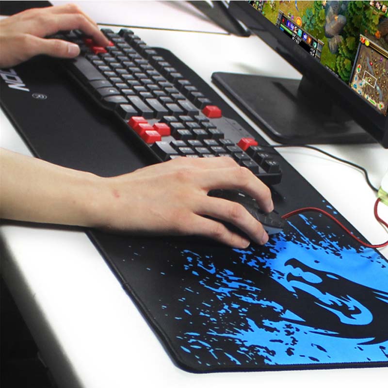 Mouse pad with black base and blue dragon art, hands using a gaming keyboard and mouse