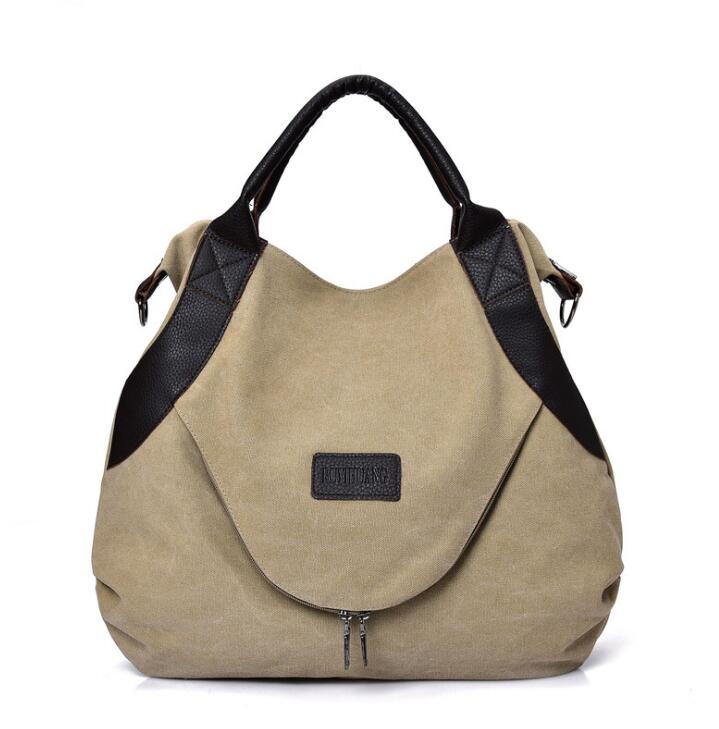 Beige canvas shoulder bag with dark trim, top handles, front patch, and small zipper pull