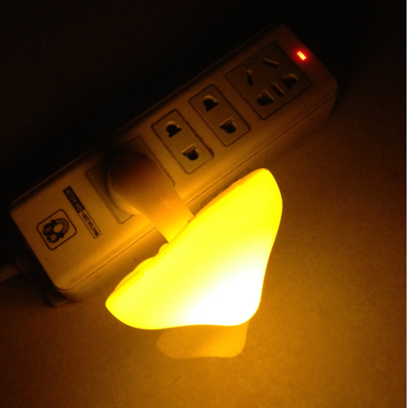 Plug-in mushroom LED night light glowing warm yellow from wall outlet