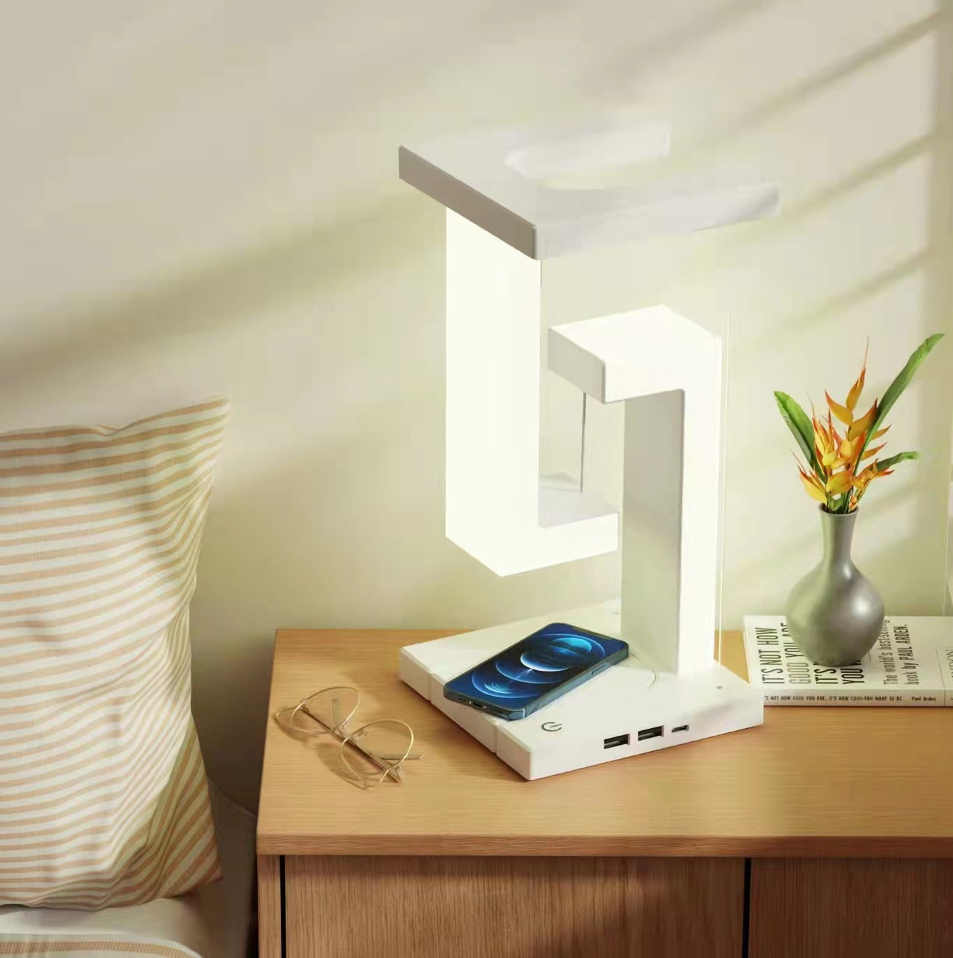 White wireless charging table lamp with glowing frame and phone charging base on tabletop