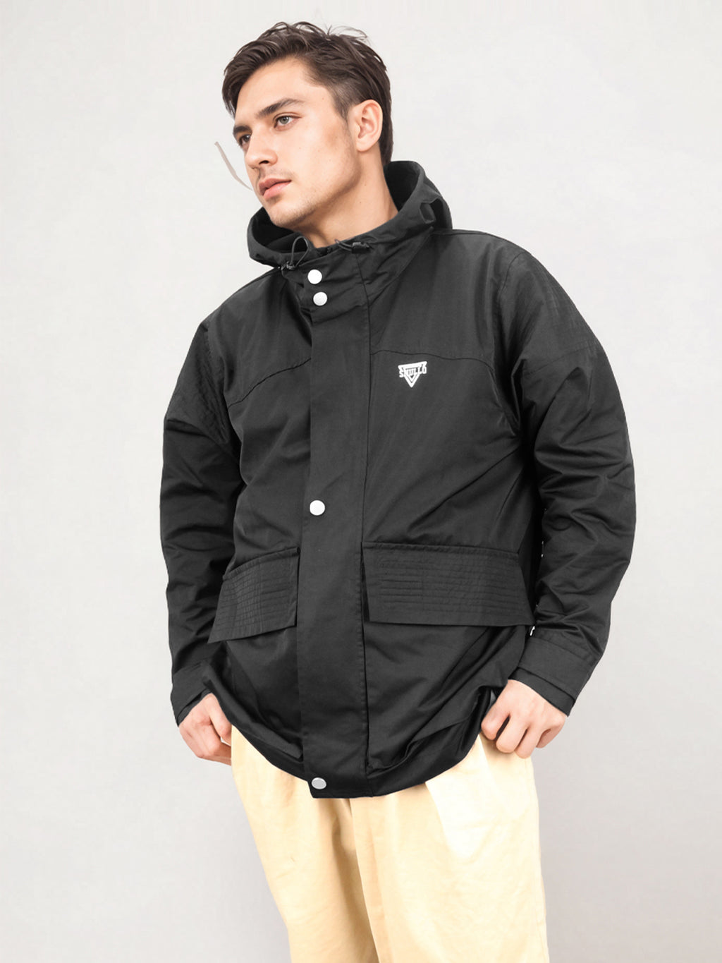 Black hooded rain jacket, angled front view with snap buttons and logo patch