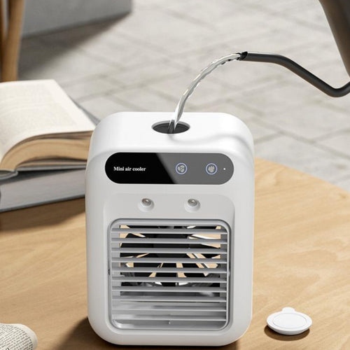 Portable mini air cooler on table with water stream routed into top inlet, white