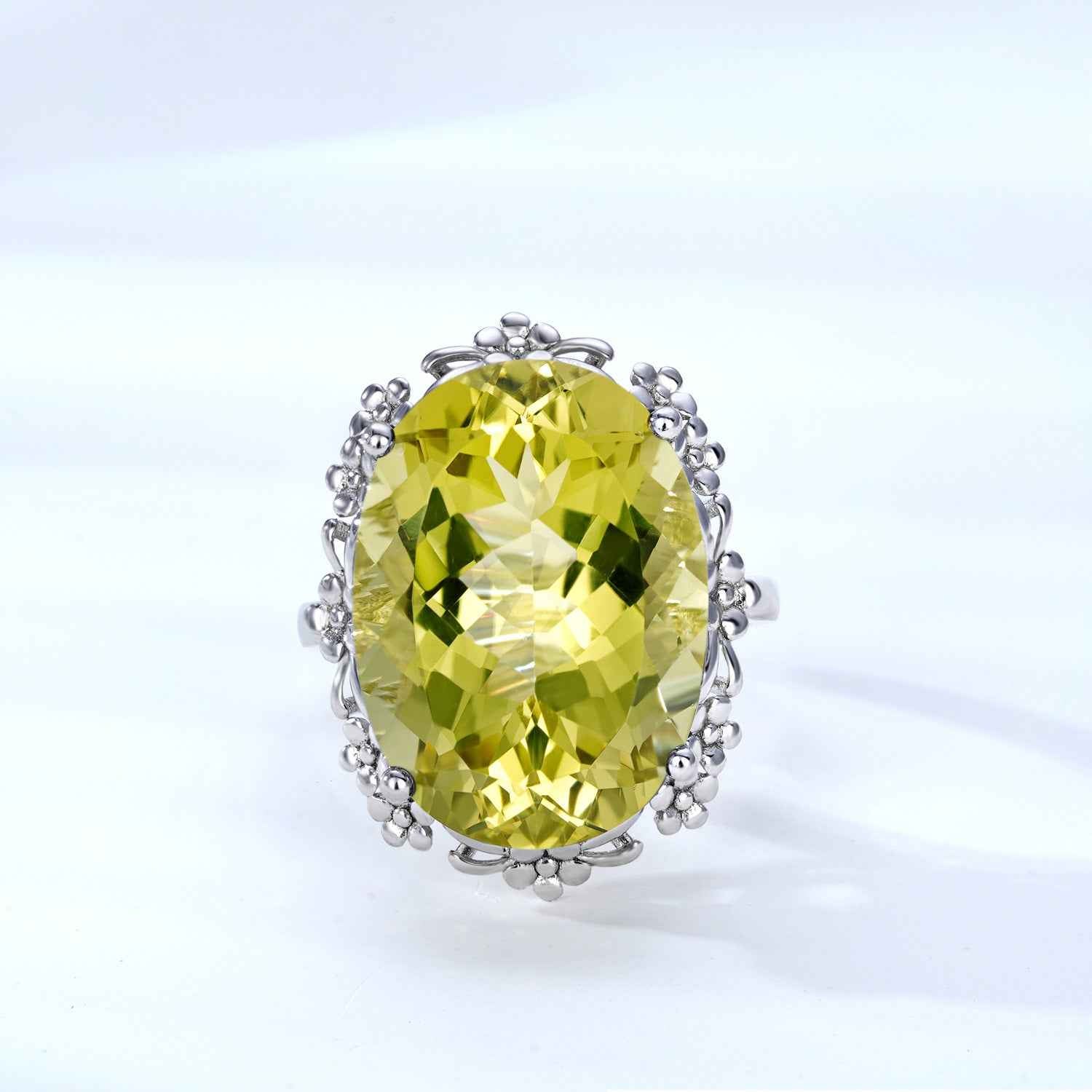 Yellow oval crystal ring with rounded silver cluster setting and faceted halo