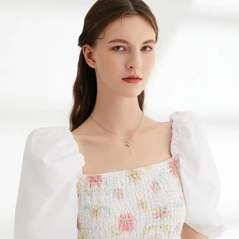 Angel wing heart necklace worn at the collar, featuring a small heart crystal charm